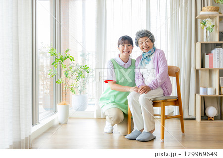 椅子に座る介護士の女性と若い介護職員 129969649