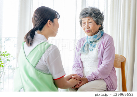 椅子に座る介護士の女性と若い介護職員 129969652