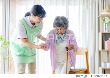 介護イメージ　杖をついて歩くシニア女性と介護士 129969653