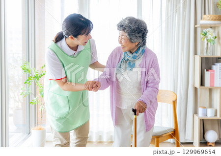 介護イメージ 杖をついて歩くシニア女性と介護士 介護イメージ 杖をついて歩くシニア女性と介護士 129969654