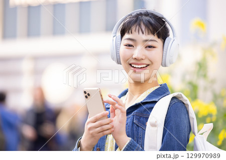 ヘッドフォンをして音楽を聴いている若い女性　 129970989