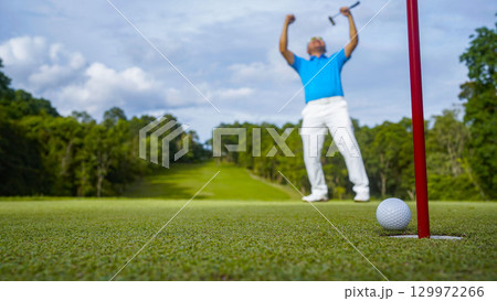 Golfer putting ball on the green golf, lens flare on sun set evening time. Golfer hitting golf ball. 129972266