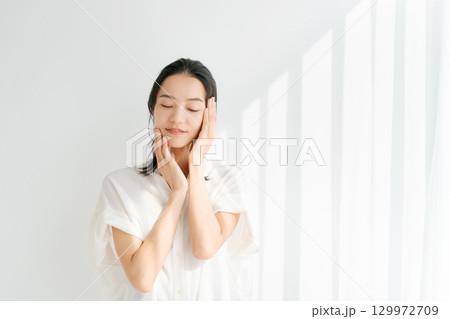 頬に手を当てる笑顔の女性 129972709