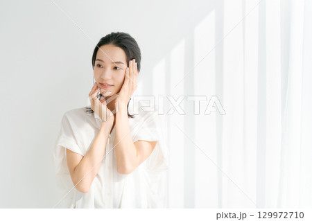 頬に手を当てる笑顔の女性 頬に手を当てる笑顔の女性 129972710