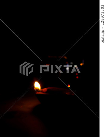Burning Clay Oil Lamp in Darkness Symbolizing Light and Hope 129973503
