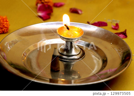 Traditional Oil Lamp Burning on Silver Plate for Puja Ritual 129973505