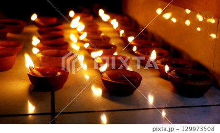 Rows of Lit Clay Oil Lamps Creating Warm Festival Glow 129973508