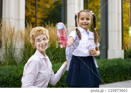 A mother with her daughter at the school, the girl holding a water bottle. 129973601