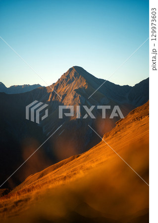 Majestic Mountain Landscape Captures Golden Light at Sunset in Serene Wilderness 129973603