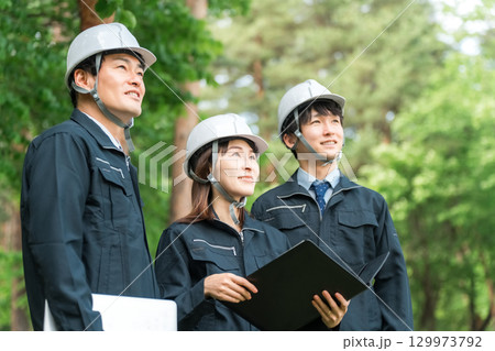 作業現場,建築現場,建設現場にいるヘルメットと作業着姿の男女スタッフ 129973792