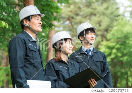作業現場,建築現場,建設現場にいるヘルメットと作業着姿の男女スタッフ 作業現場,建築現場,建設現場にいるヘルメットと作業着姿の男女スタッフ 129973793