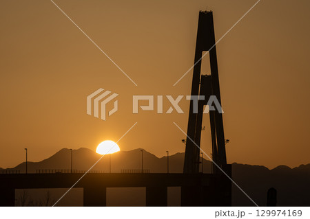 立山連峰から昇る朝日と新湊大橋 129974169