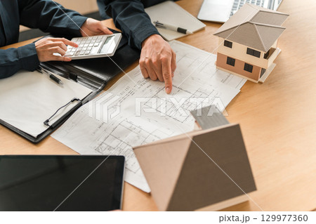 住宅模型,設計図の前で会議,ミーティングをするビジネスマン 住宅模型,設計図の前で会議,ミーティングをするビジネスマン 129977360