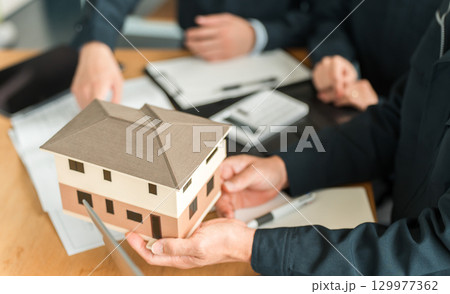 住宅模型,設計図の前で会議,ミーティングをするビジネスマン 129977362