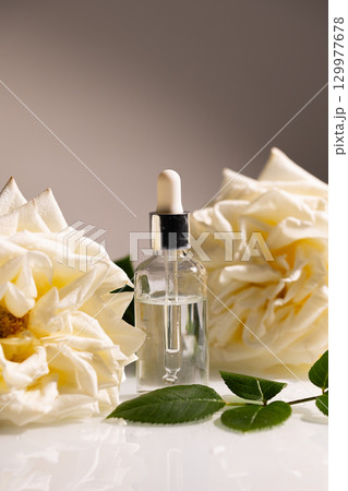 Luxurious Rose Oil for Skin Care With Beautiful White Roses Beside the Bottle Luxurious Rose Oil for Skin Care With Beautiful White Roses Beside the Bottle 129977678