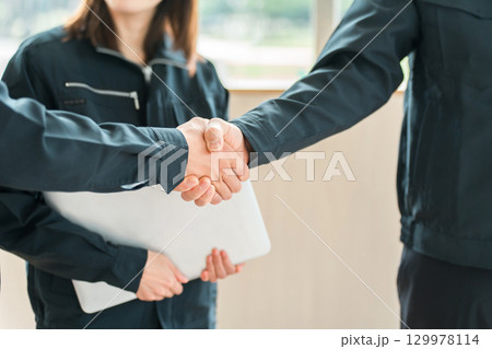 握手をする作業着姿の男女のビジネスマン,作業員 129978114
