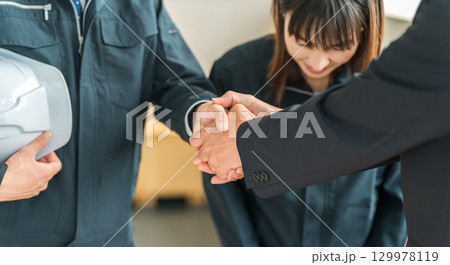 握手をする作業着姿の男女のビジネスマン,作業員 129978119