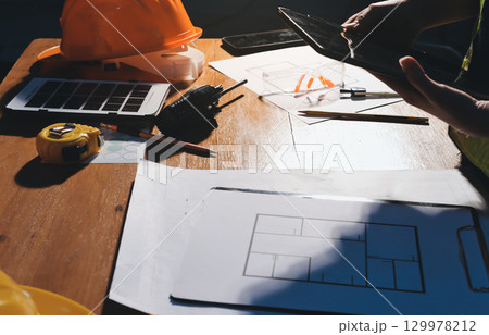 Closeup of team of industrial engineers meeting analyze machinery blueprints consult project on table in manufacturing factory. Working in manufacturing plant or production plant. Closeup of team of industrial engineers meeting analyze machinery blueprints consult project on table in manufacturing factory. Working in manufacturing plant or production plant. 129978212
