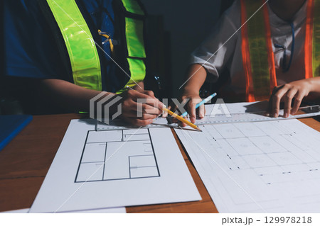 Closeup of team of industrial engineers meeting analyze machinery blueprints consult project on table in manufacturing factory. Working in manufacturing plant or production plant. Closeup of team of industrial engineers meeting analyze machinery blueprints consult project on table in manufacturing factory. Working in manufacturing plant or production plant. 129978218