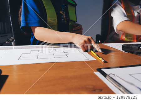 Closeup of team of industrial engineers meeting analyze machinery blueprints consult project on table in manufacturing factory. Working in manufacturing plant or production plant. Closeup of team of industrial engineers meeting analyze machinery blueprints consult project on table in manufacturing factory. Working in manufacturing plant or production plant. 129978225