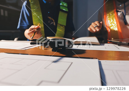 Closeup of team of industrial engineers meeting analyze machinery blueprints consult project on table in manufacturing factory. Working in manufacturing plant or production plant. 129978226