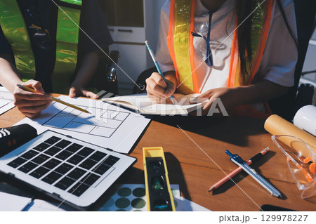 Closeup of team of industrial engineers meeting analyze machinery blueprints consult project on table in manufacturing factory. Working in manufacturing plant or production plant. Closeup of team of industrial engineers meeting analyze machinery blueprints consult project on table in manufacturing factory. Working in manufacturing plant or production plant. 129978227