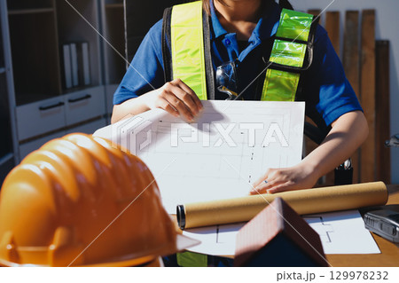 Closeup of team of industrial engineers meeting analyze machinery blueprints consult project on table in manufacturing factory. Working in manufacturing plant or production plant. 129978232