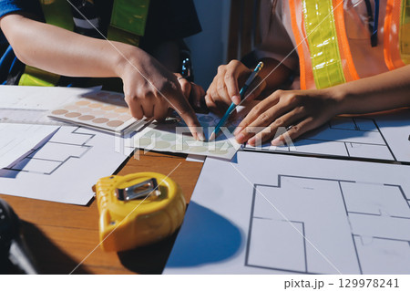 Closeup of team of industrial engineers meeting analyze machinery blueprints consult project on table in manufacturing factory. Working in manufacturing plant or production plant. 129978241