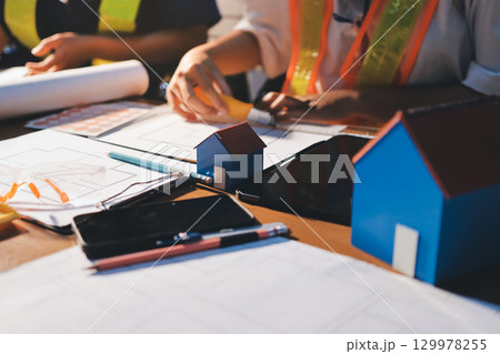 Closeup of team of industrial engineers meeting analyze machinery blueprints consult project on table in manufacturing factory. Working in manufacturing plant or production plant. Closeup of team of industrial engineers meeting analyze machinery blueprints consult project on table in manufacturing factory. Working in manufacturing plant or production plant. 129978255