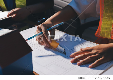 Closeup of team of industrial engineers meeting analyze machinery blueprints consult project on table in manufacturing factory. Working in manufacturing plant or production plant. Closeup of team of industrial engineers meeting analyze machinery blueprints consult project on table in manufacturing factory. Working in manufacturing plant or production plant. 129978285
