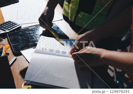 Closeup of team of industrial engineers meeting analyze machinery blueprints consult project on table in manufacturing factory. Working in manufacturing plant or production plant. 129978291
