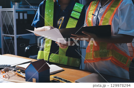 Closeup of team of industrial engineers meeting analyze machinery blueprints consult project on table in manufacturing factory. Working in manufacturing plant or production plant. 129978294