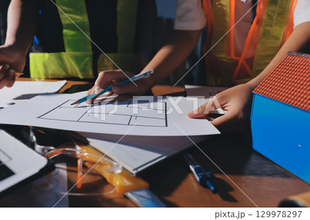Closeup of team of industrial engineers meeting analyze machinery blueprints consult project on table in manufacturing factory. Working in manufacturing plant or production plant. Closeup of team of industrial engineers meeting analyze machinery blueprints consult project on table in manufacturing factory. Working in manufacturing plant or production plant. 129978297