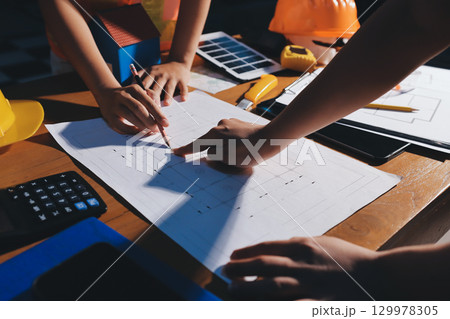 Closeup of team of industrial engineers meeting analyze machinery blueprints consult project on table in manufacturing factory. Working in manufacturing plant or production plant. 129978305