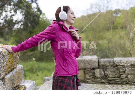 Woman wearing headphones listening to music while hiking in nature 129979979