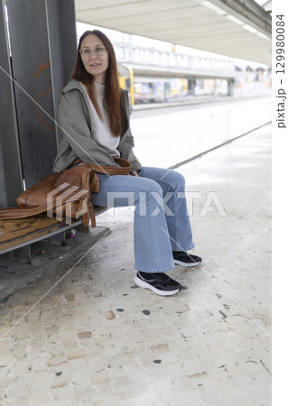 Woman waiting for transportation at train station or bus stop Woman waiting for transportation at train station or bus stop 129980084