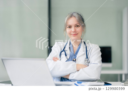 Female doctor sitting at a desk, looking at the camera. 129980399
