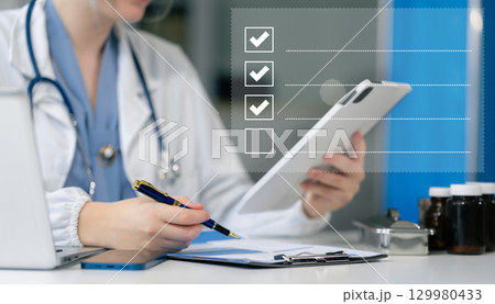 doctor woman using tablet to do online checklist survey, doing assessment online survey answer test questions Digital form. doctor woman using tablet to do online checklist survey, doing assessment online survey answer test questions Digital form. 129980433