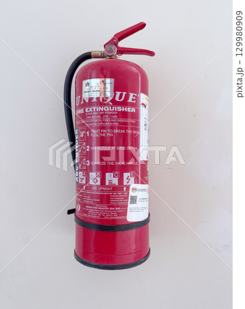 Red fire extinguisher mounted on a wall with clear instructions 129980909