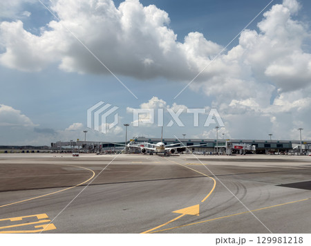 A busy day at Changi Airport with aircraft on the tarmac under a cloudy sky 129981218