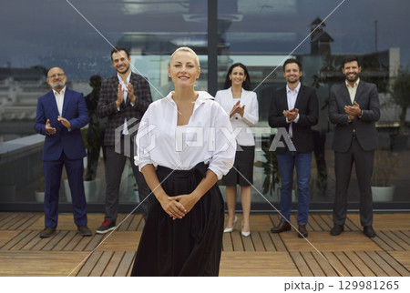 Confident female leader applauded by diverse business team on rooftop terrace 129981265