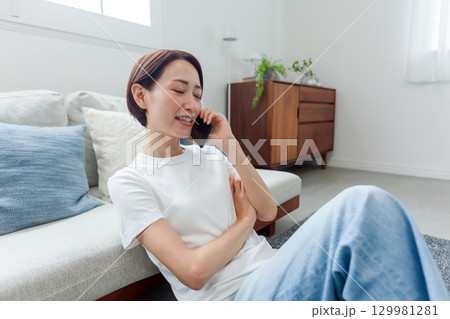 部屋で電話をする若い女性 部屋で電話をする若い女性 129981281