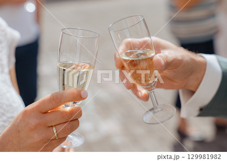 Two people clinking champagne glasses in a celebratory toast. The atmosphere suggests a joyous occasion, possibly a wedding or special event, marked by shared happiness and connection Two people clinking champagne glasses in a celebratory toast. The atmosphere suggests a joyous occasion, possibly a wedding or special event, marked by shared happiness and connection 129981982