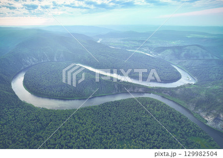 Captivating river meander curves through lush forest landscape in early morning light, showcasing stunning natural beauty. The Mana River and the Manskaya Loop in Siberia, Russia Krasnoyarsk. 129982504