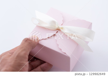 ピンク色のプレゼントを持つ手 129982649