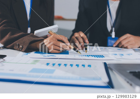 Focused young businessman signing agreement with skilled lawyer in eyeglasses. Concentrated financial advisor showing place for signature on paper contract document to male client at meeting in office 129983129