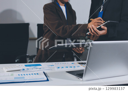Focused young businessman signing agreement with skilled lawyer in eyeglasses. Concentrated financial advisor showing place for signature on paper contract document to male client at meeting in office 129983137