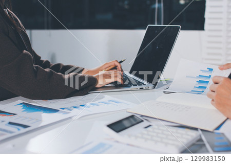 Focused young businessman signing agreement with skilled lawyer in eyeglasses. Concentrated financial advisor showing place for signature on paper contract document to male client at meeting in office 129983150