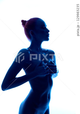 Silhouette of a woman posed gracefully in soft blue light 129983235