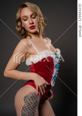 Beautiful woman in red lingerie poses sensually against a dark background 129983239